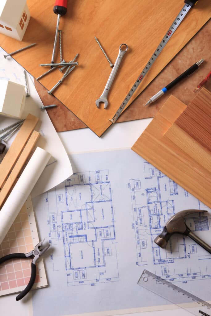 Rénovation Maison : Plans, Outils & Matériaux de Construction Plans de maison avec outils de construction (vis, tournevis, marteau, mètre) et matériaux (bois, carrelage). Maquette maison et dimensions visibles.